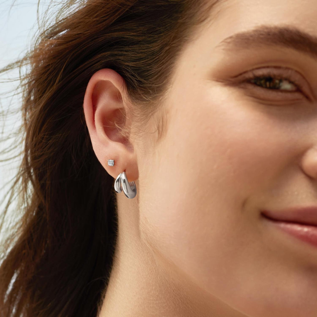 Close-up of a woman wearing silver earrings with a blurred background