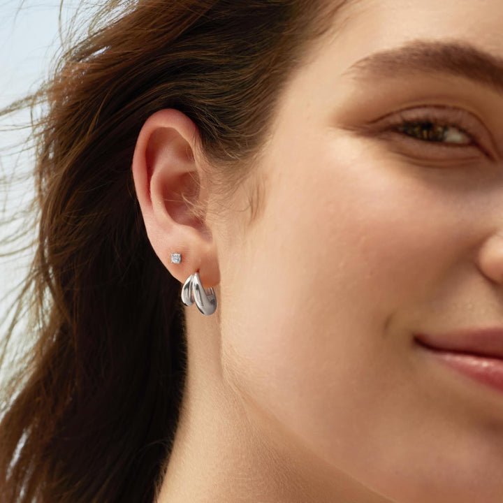 Close-up of a woman wearing silver earrings with a blurred background