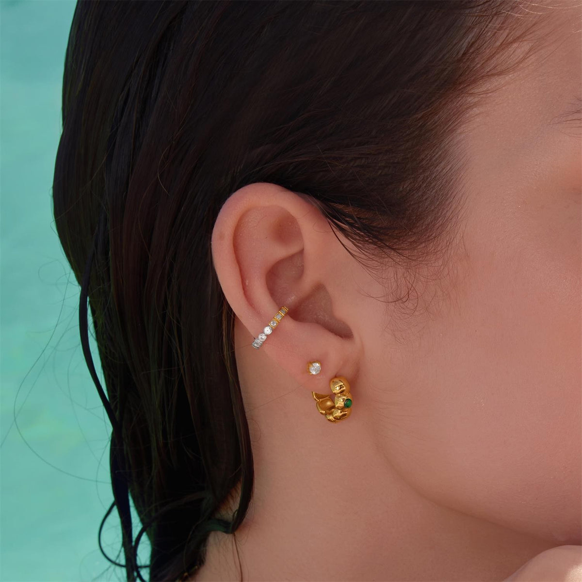 Close-up of an ear wearing gold earrings with a blurred background