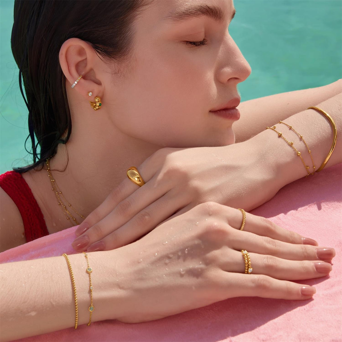 Woman wearing gold jewelry with a pool in the background
