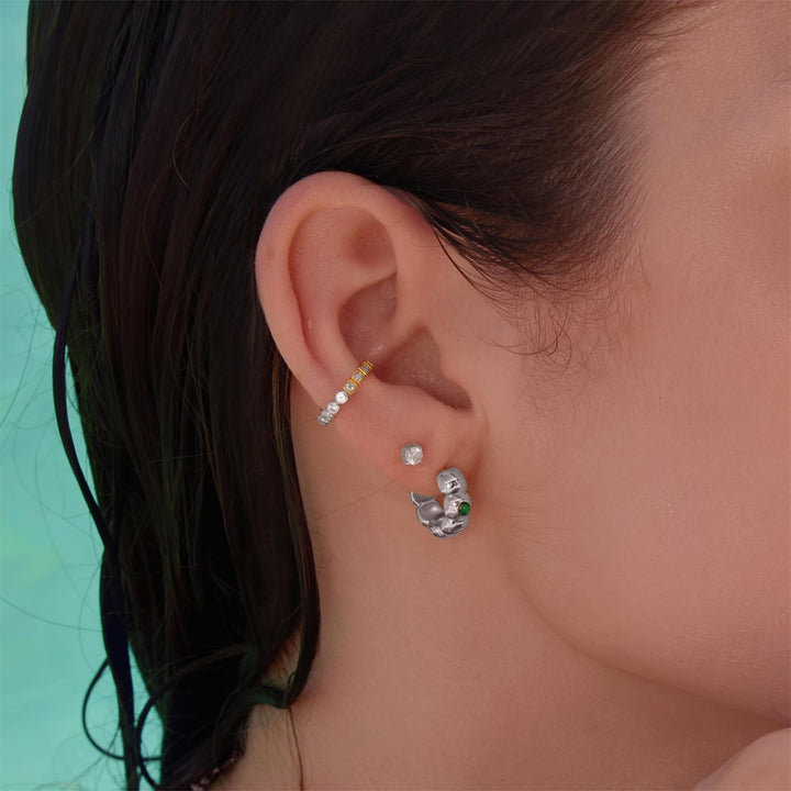 Close-up of an ear wearing multiple earrings with a blurred background