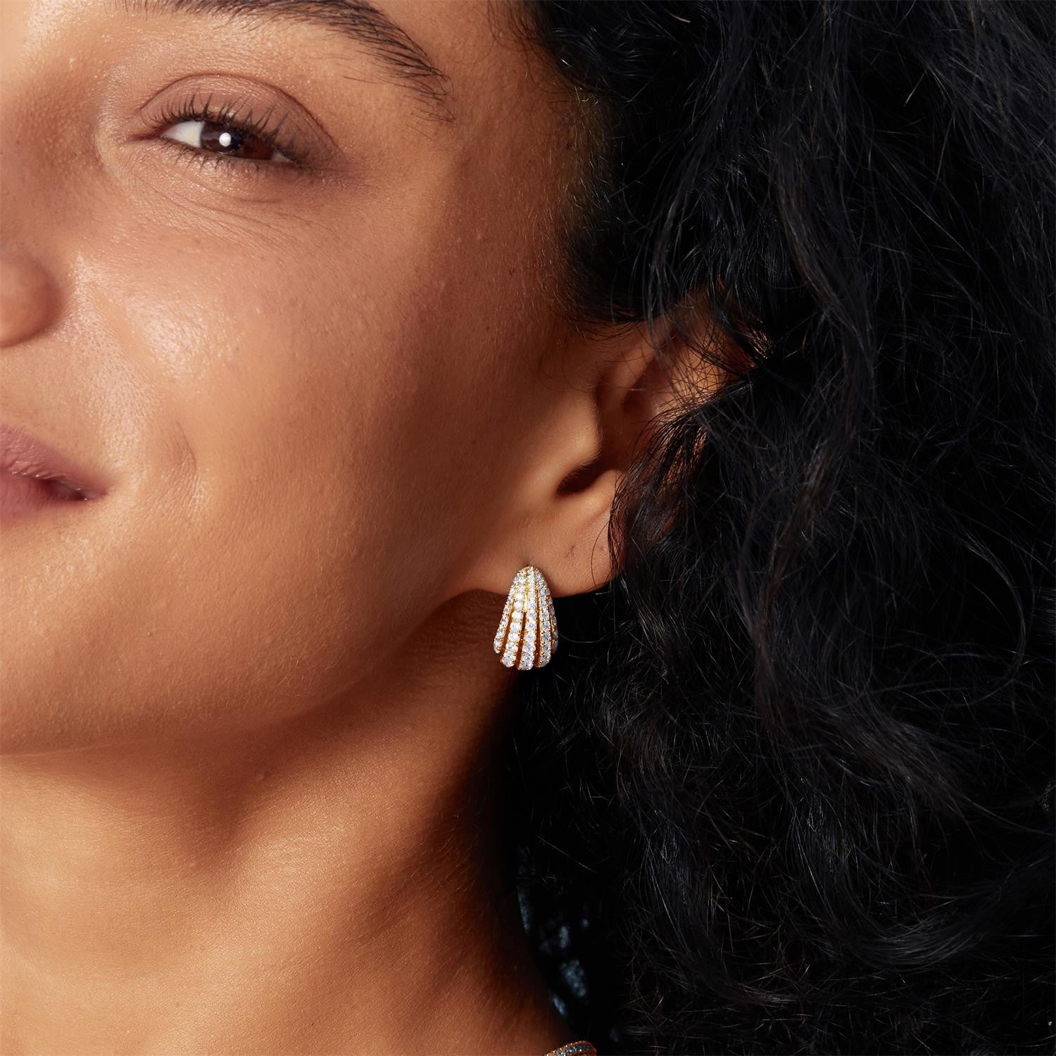 Close-up of a woman wearing a diamond earring with a dark background