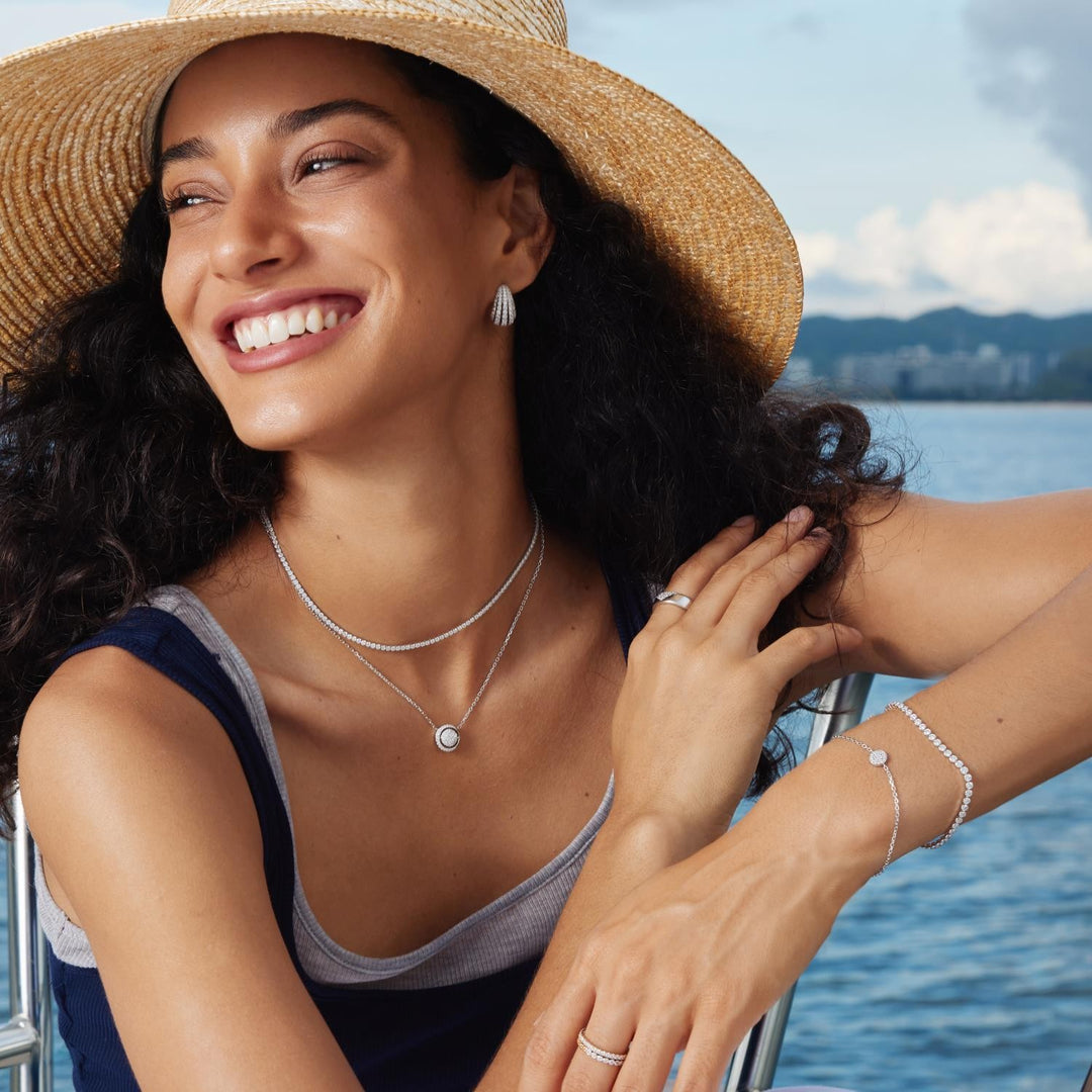 Woman wearing jewelry by a body of water with mountains in the background