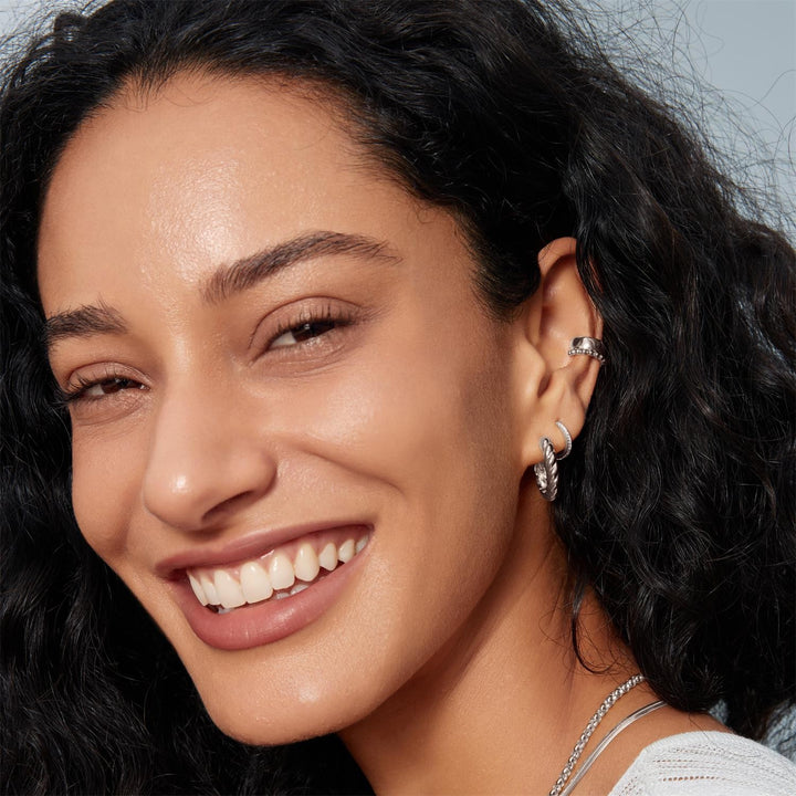 Close-up of a woman with dark hair and earrings, wearing a silver necklace.