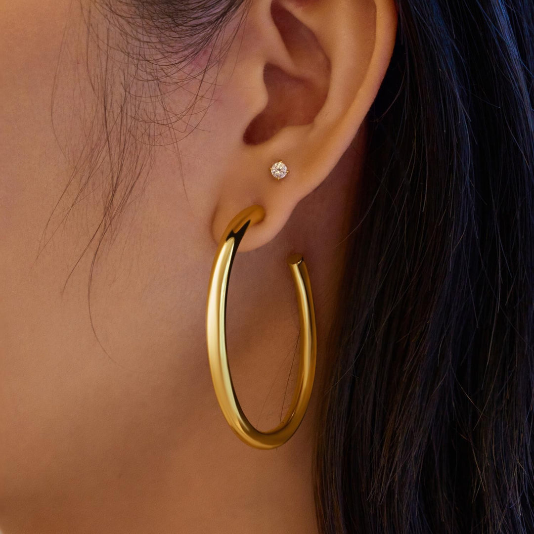 Gold hoop earring worn by a person with dark hair.