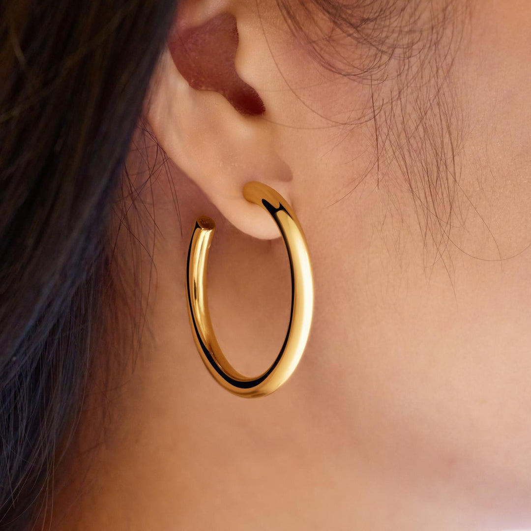 Gold hoop earring worn by a person with dark hair.