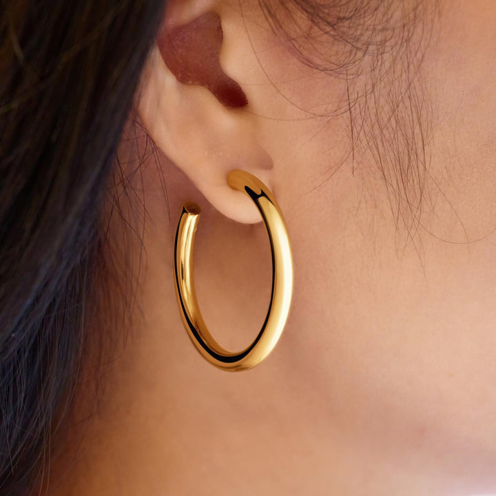 Gold hoop earring worn by a person with dark hair.