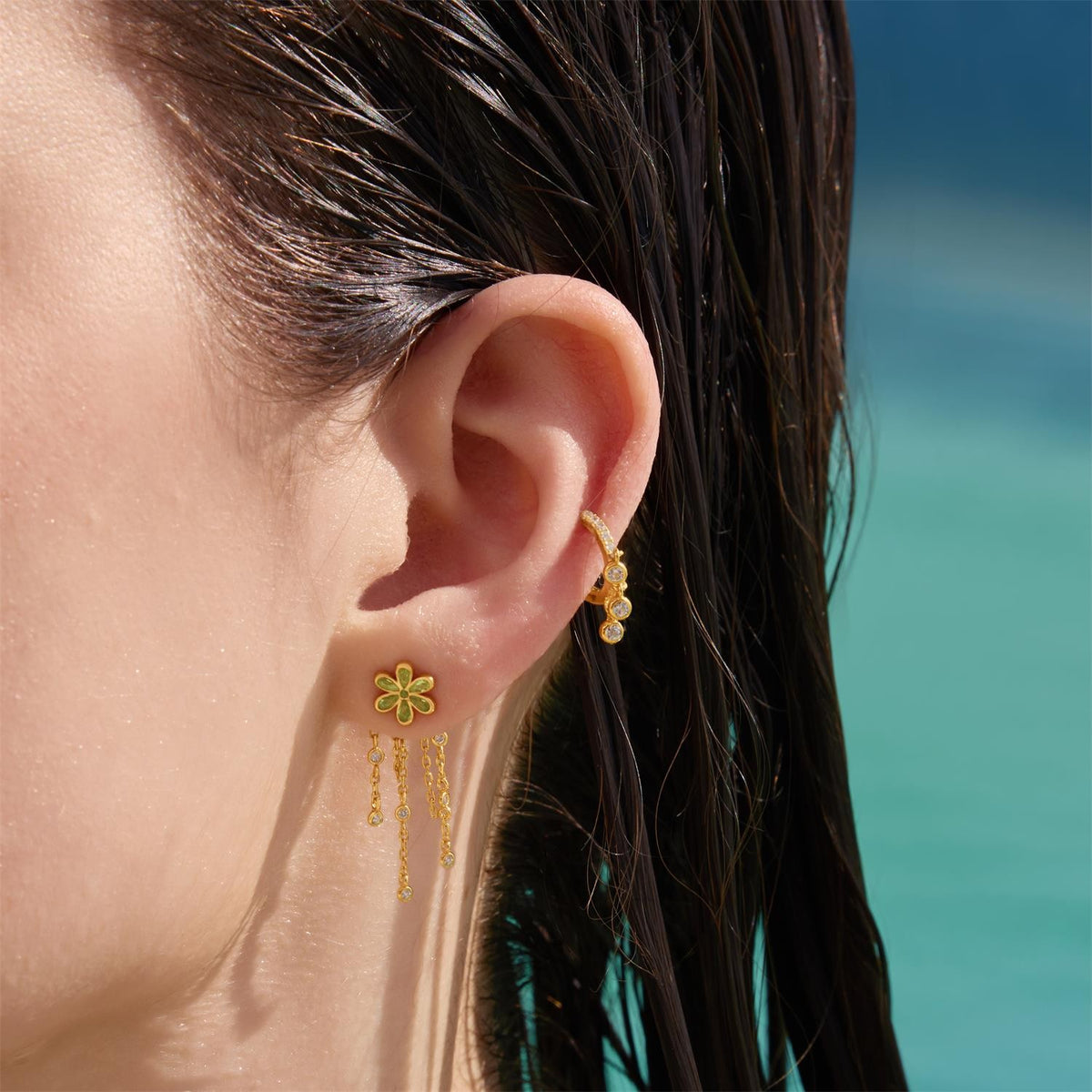Close-up of a person wearing gold floral earrings with a blurred background