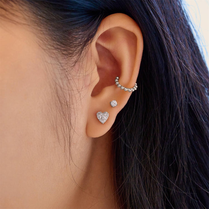 Close-up of an ear wearing multiple diamond earrings with dark hair.