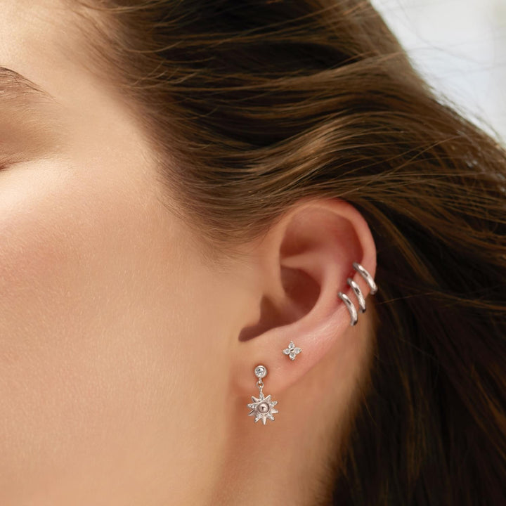 Close-up of an ear with silver earrings and hair partially covering the side of the face.