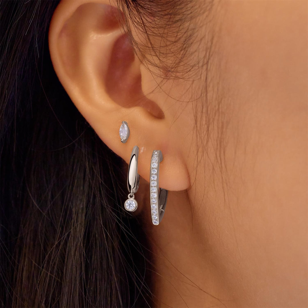 Close-up of an ear wearing multiple silver earrings with a blurred background
