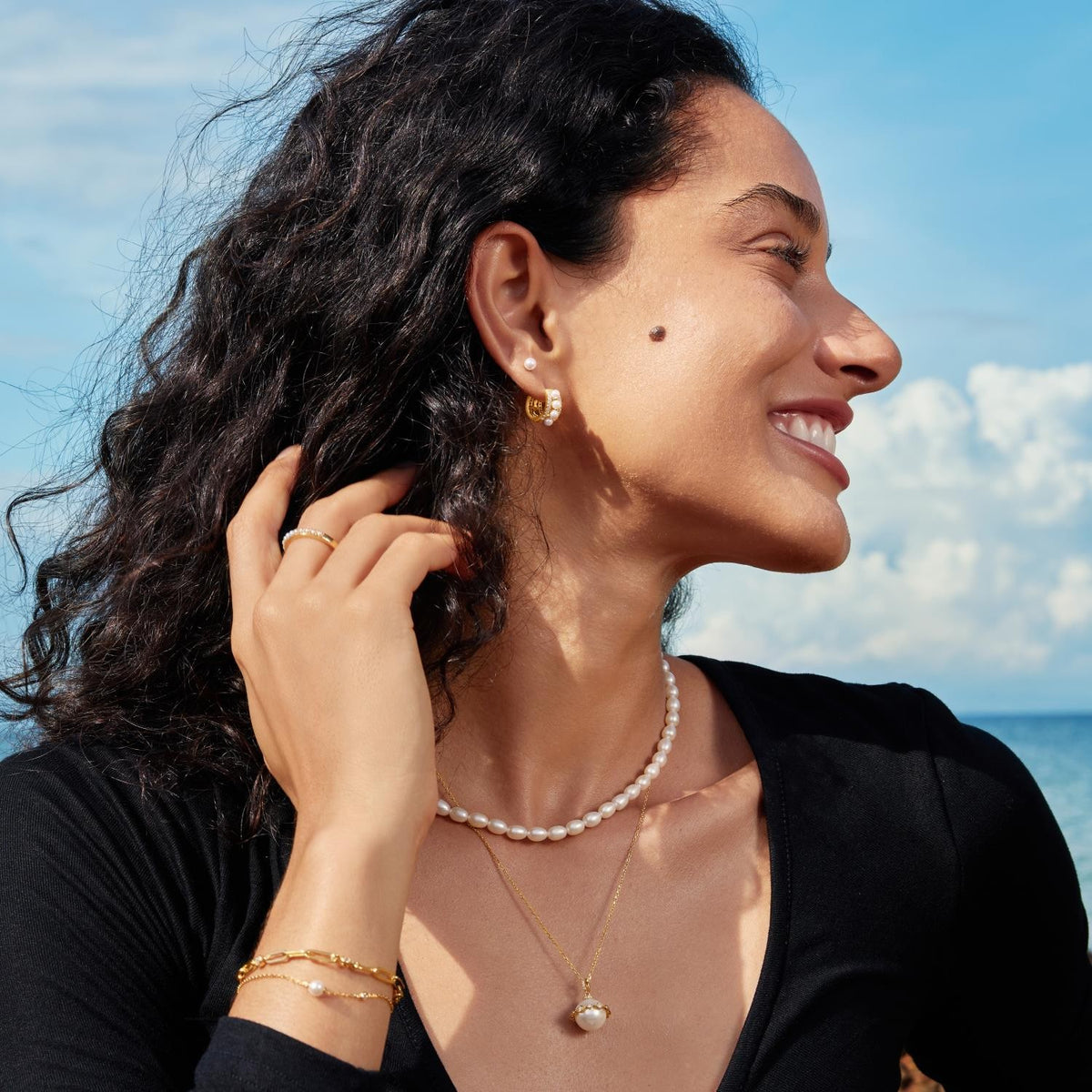 Woman wearing jewelry with a blue sky and clouds in the background