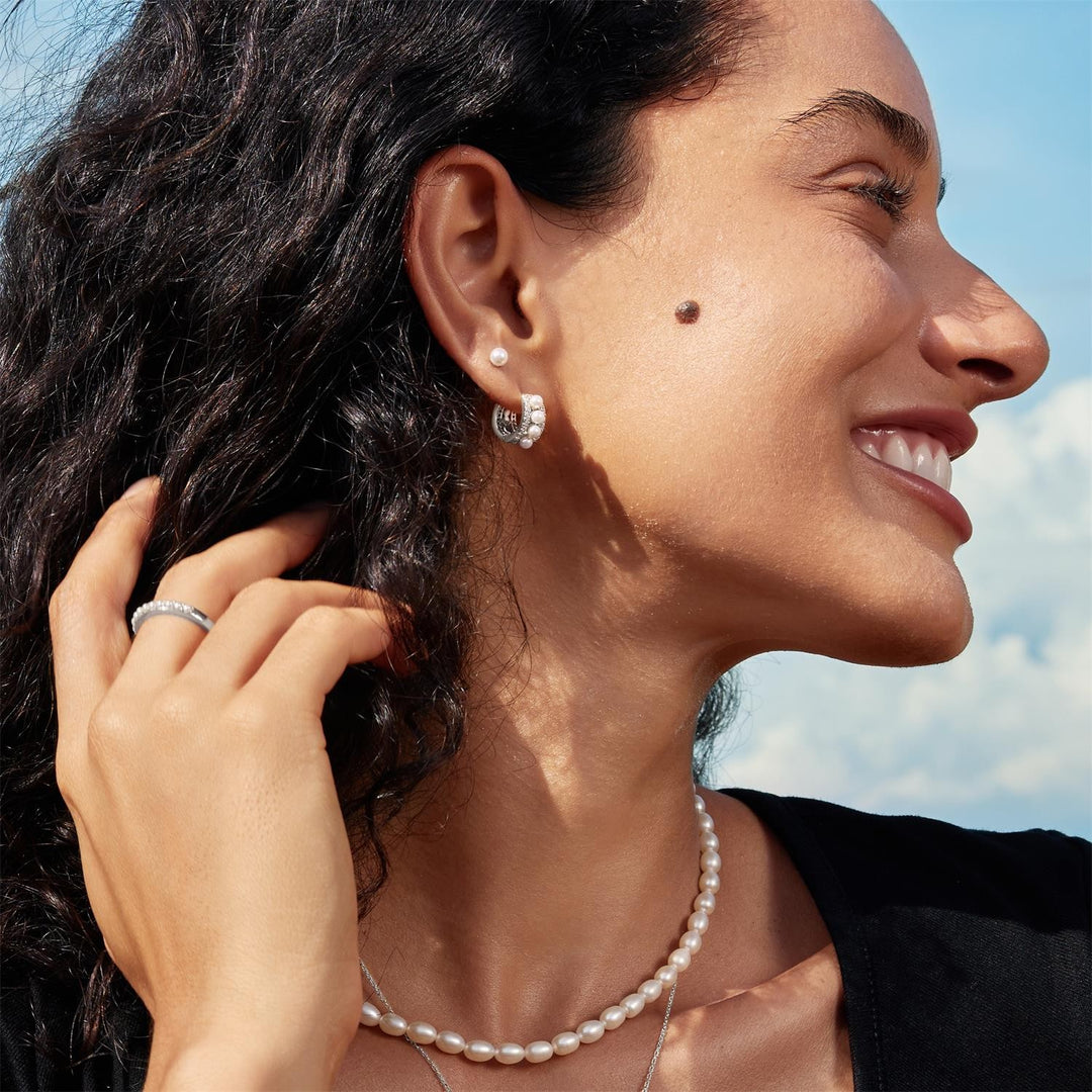 Woman wearing a pearl earring and necklace with a blue sky background