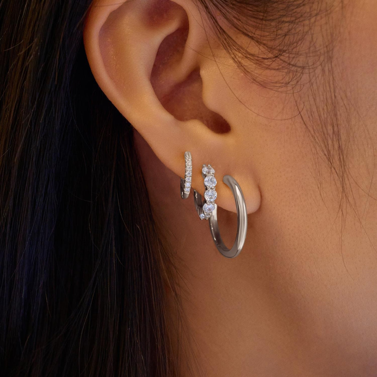 Close-up of an ear wearing two silver hoop earrings.