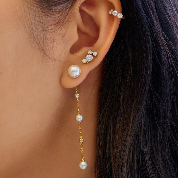 Close-up of an ear wearing pearl and diamond earrings with a blurred background