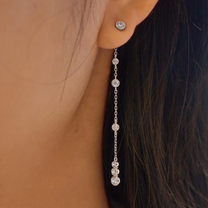 Silver chain earring with clear stones worn by a person