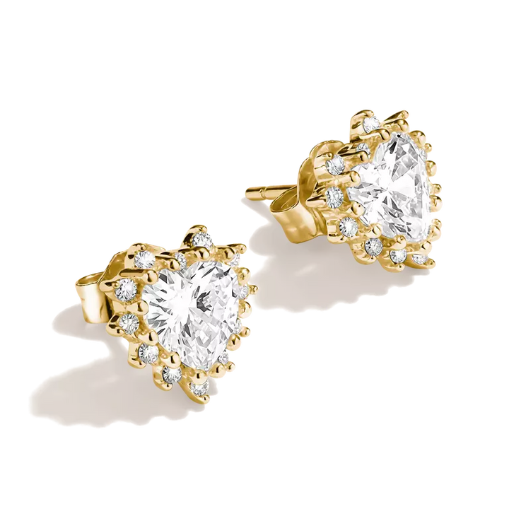 A pair of gold heart-shaped stud earrings featuring large clear marquise-cut center stones surrounded by smaller clear accent stones, shown on a clean white background.