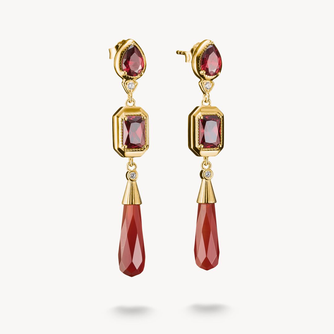 Gold earrings with red gemstones on a white background
