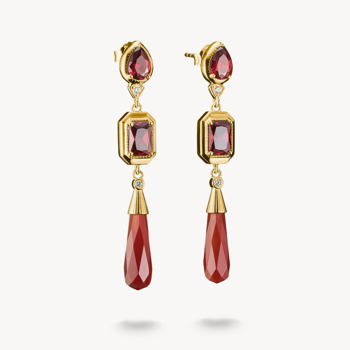 Gold earrings with red gemstones on a white background