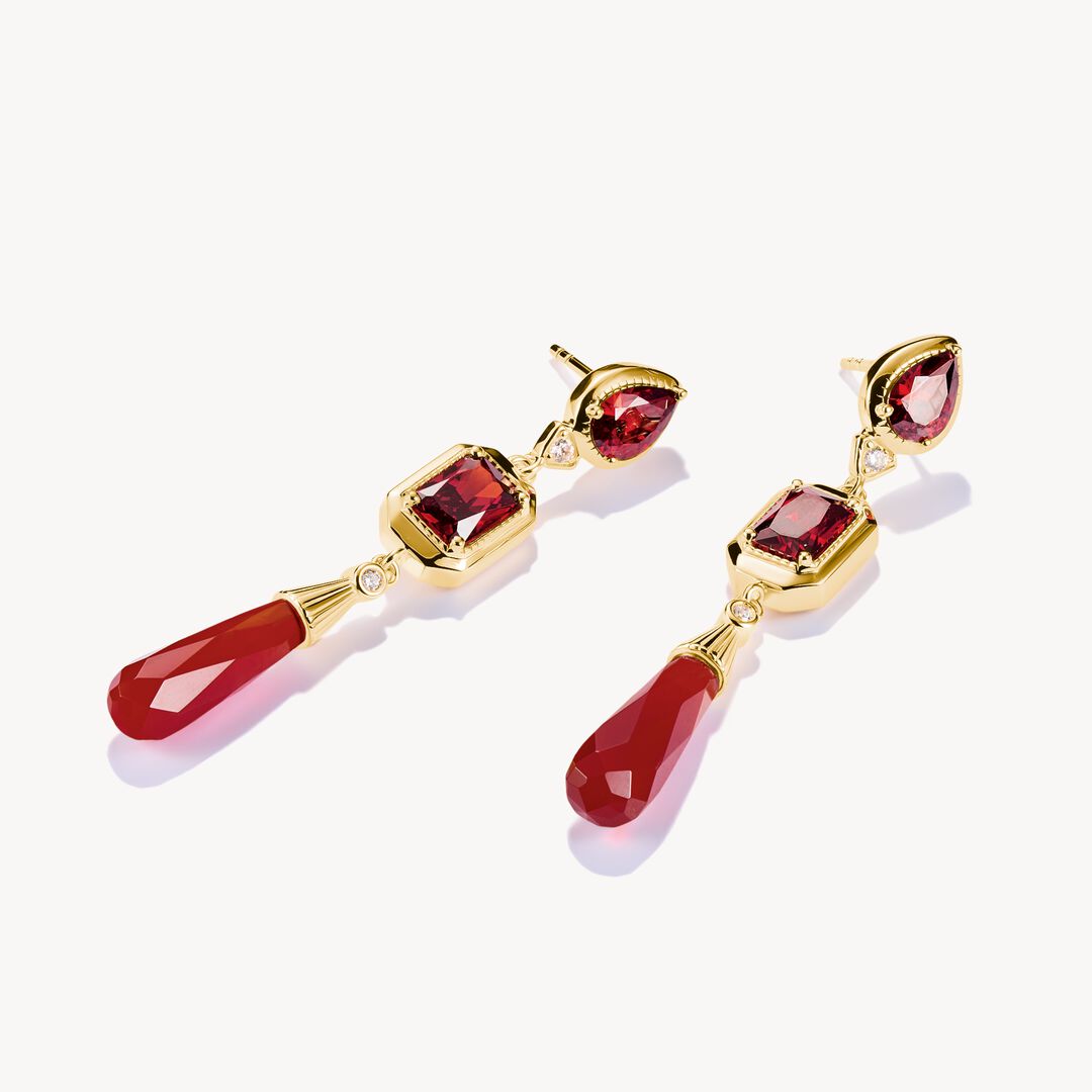 Gold earrings with red gemstones on a white background