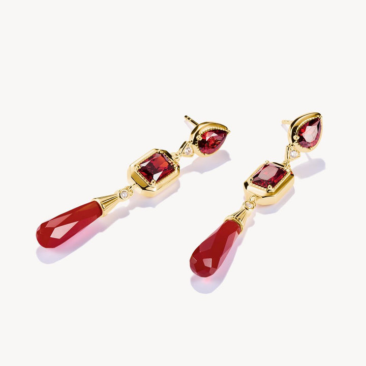 Gold earrings with red gemstones on a white background