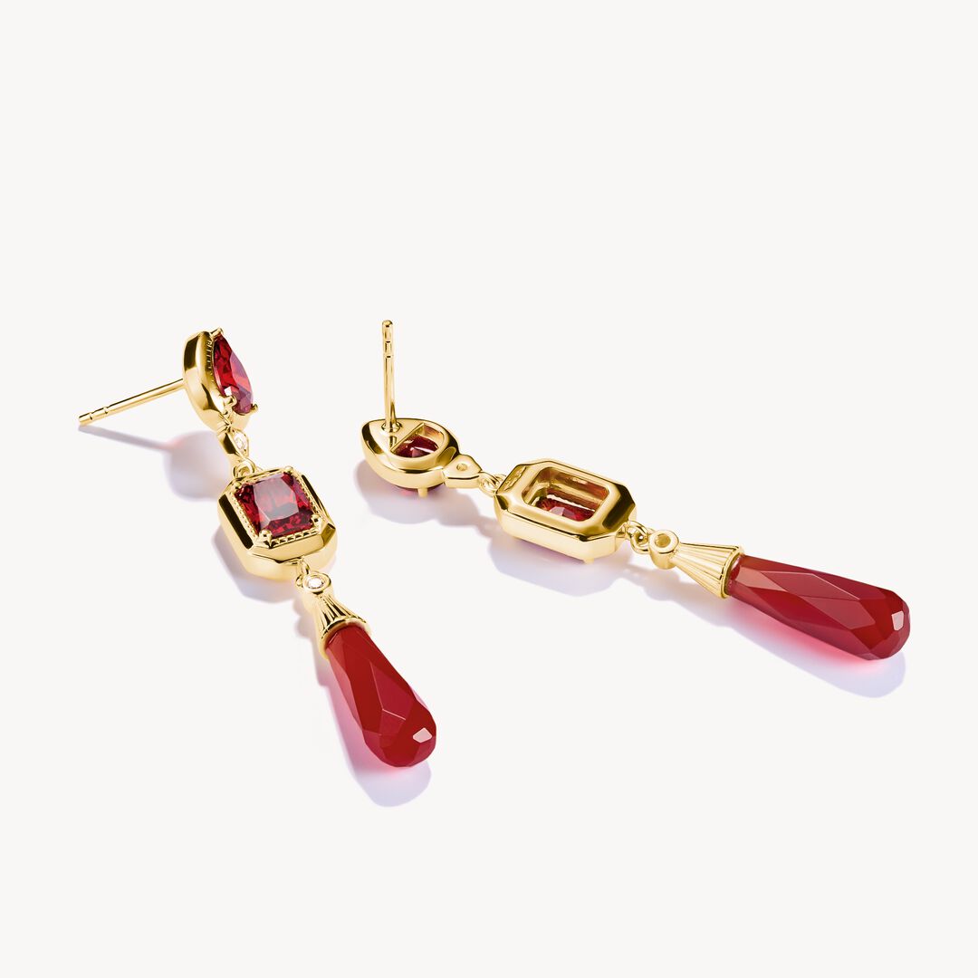 Gold earrings with red gemstones on a white background