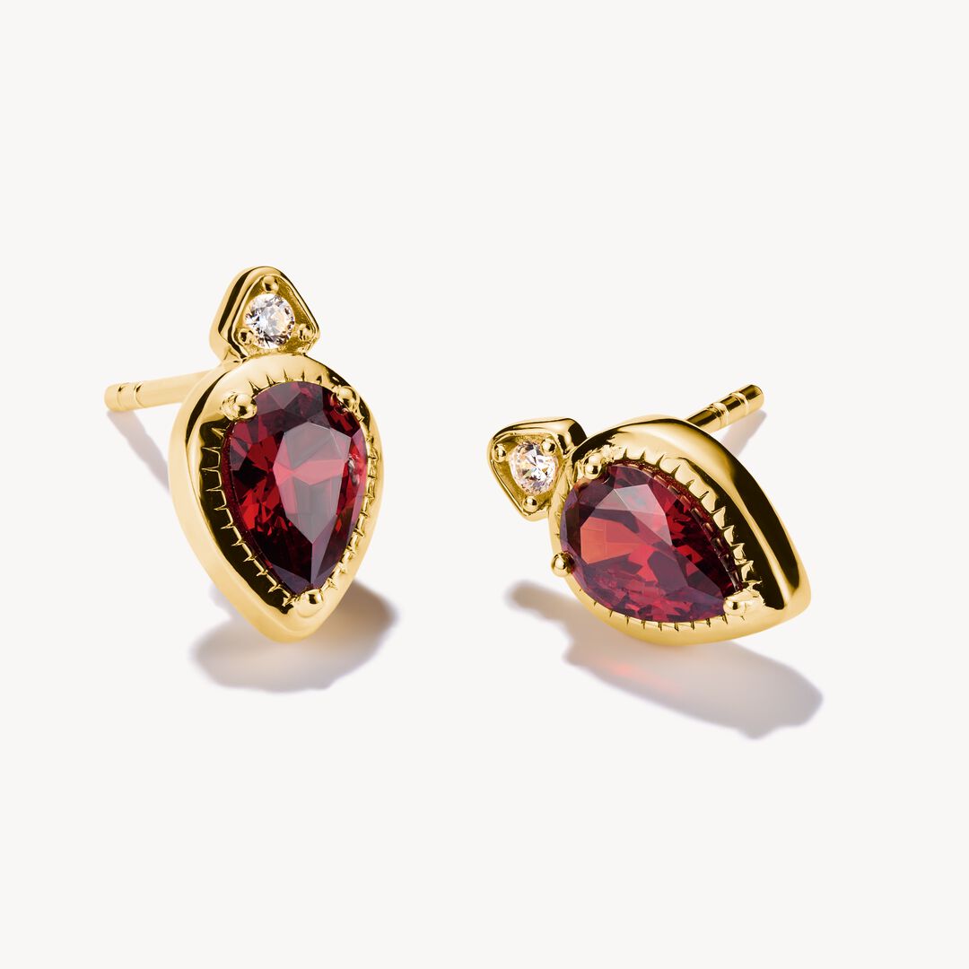 Gold earrings with red gemstones on a white background