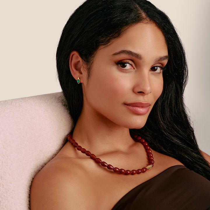 Woman wearing a red beaded necklace and earrings against a neutral background