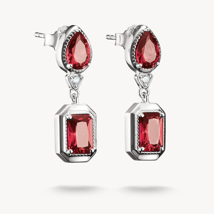 Pair of earrings with red gemstones and silver settings on a white background
