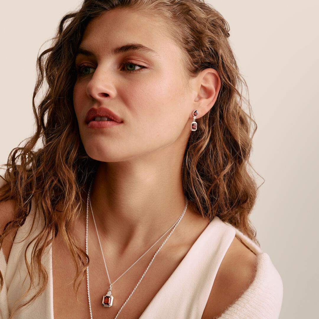 Woman wearing a necklace and earrings with a neutral background