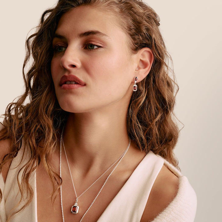 Woman wearing a necklace and earrings with a neutral background