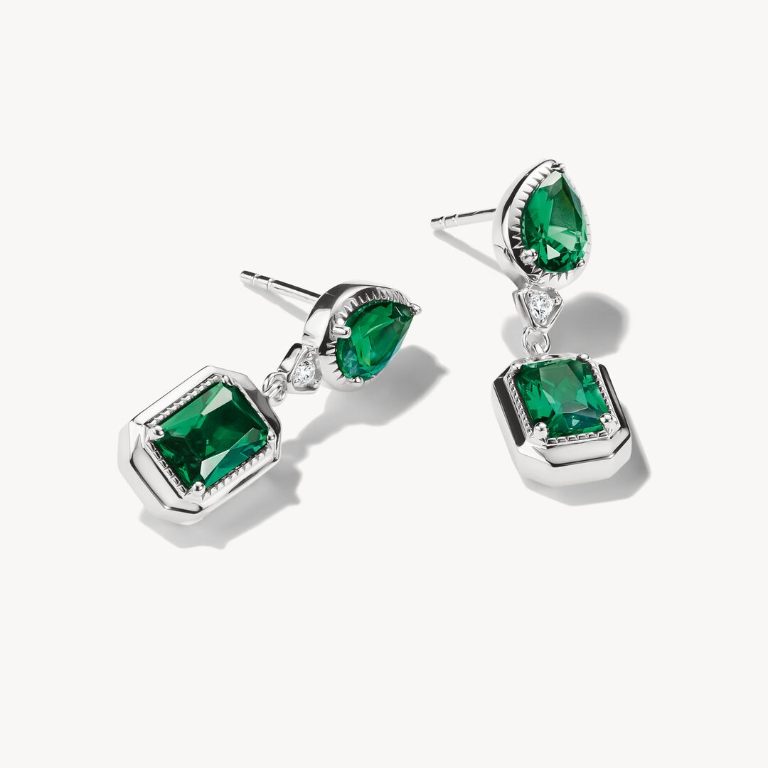 Pair of emerald green gemstone earrings on a white background