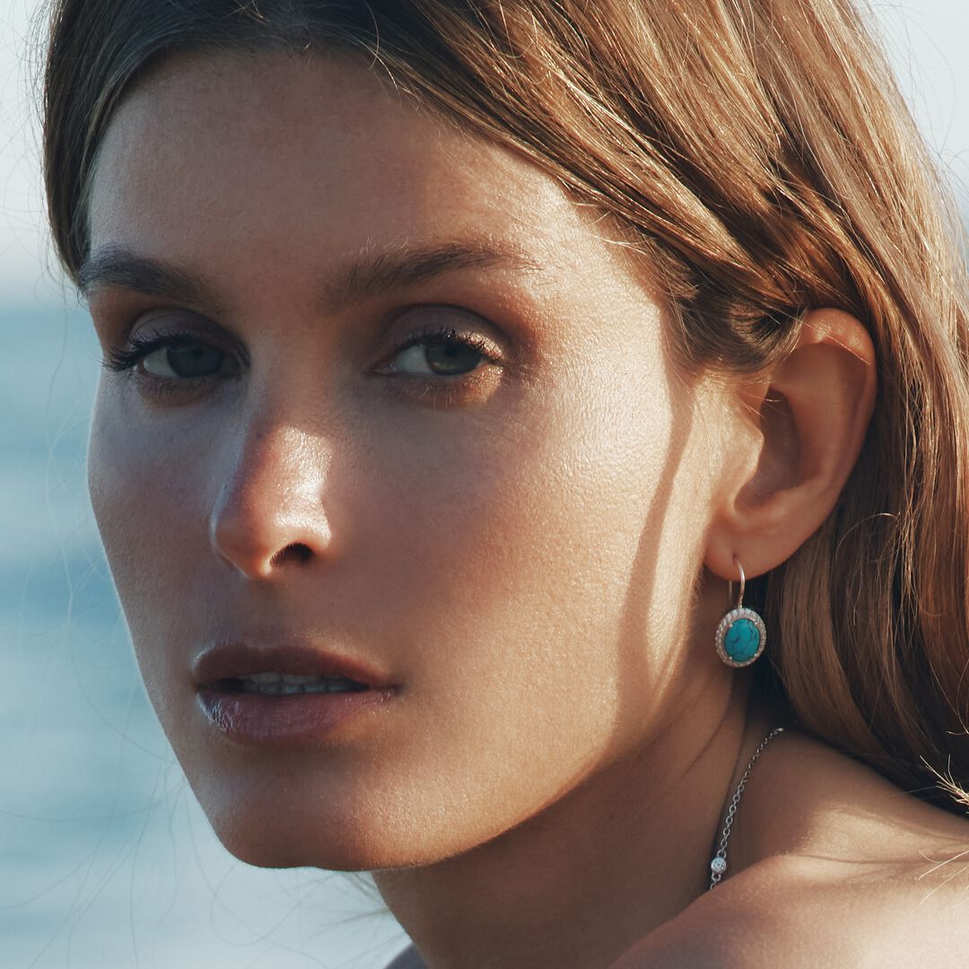 Close-up of a woman wearing turquoise earrings with a blurred background
