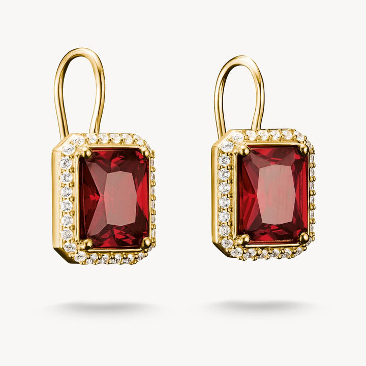 Gold earrings with red gemstones on a white background
