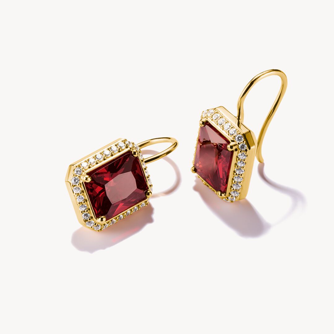 Gold earrings with red gemstones on a white background