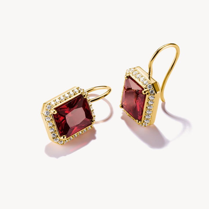 Gold earrings with red gemstones on a white background