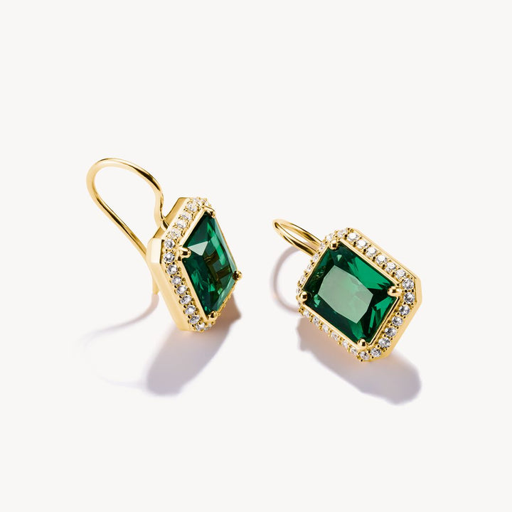 Gold earrings with green gemstones on a white background