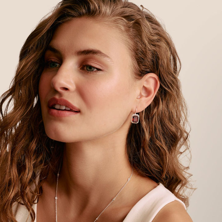 Close-up of a woman wearing earrings with a neutral background