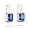 A pair of silver drop earrings featuring rectangular blue gemstones in a bezel setting with a delicate border, shown against a plain white background.