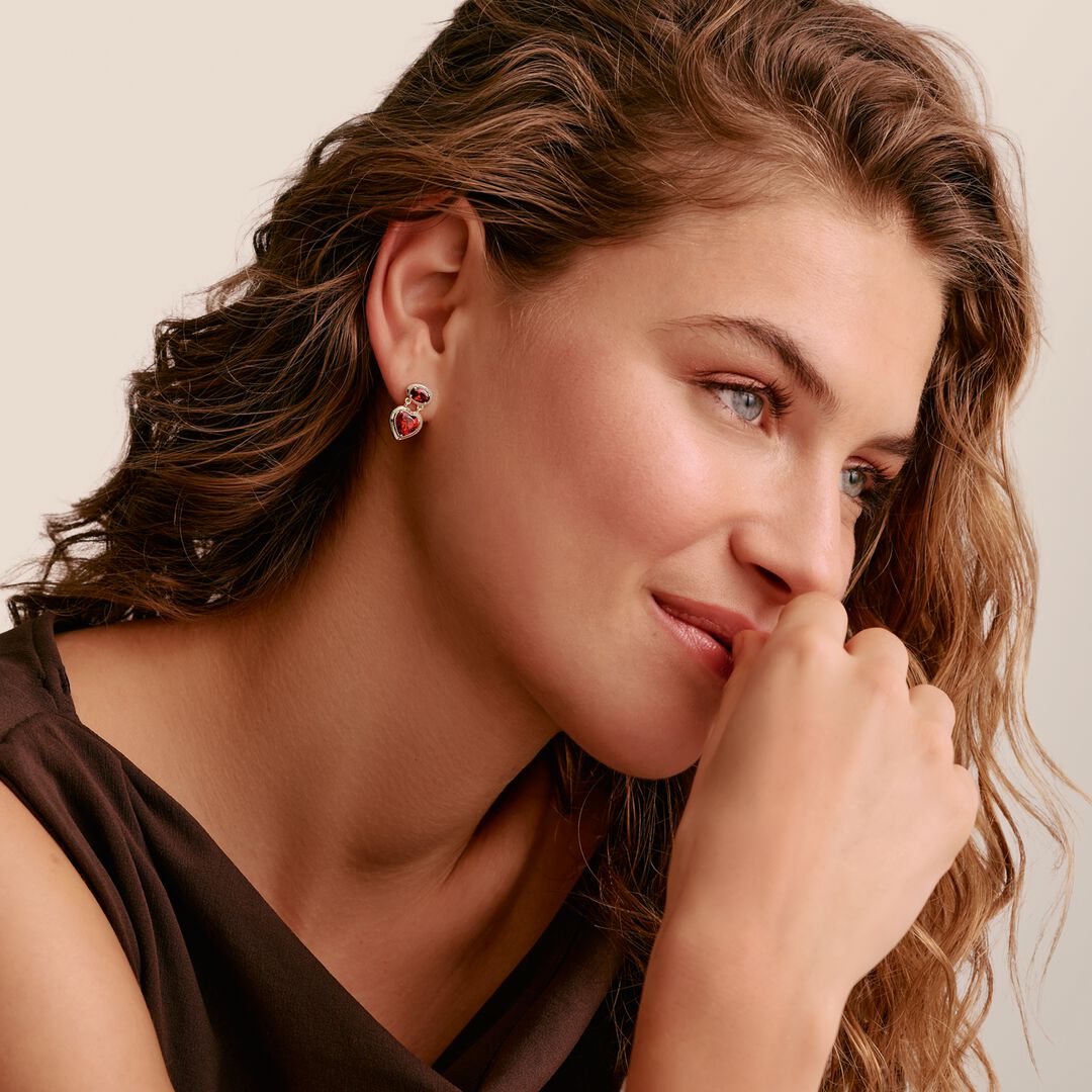 Woman wearing a pair of earrings with a beige background
