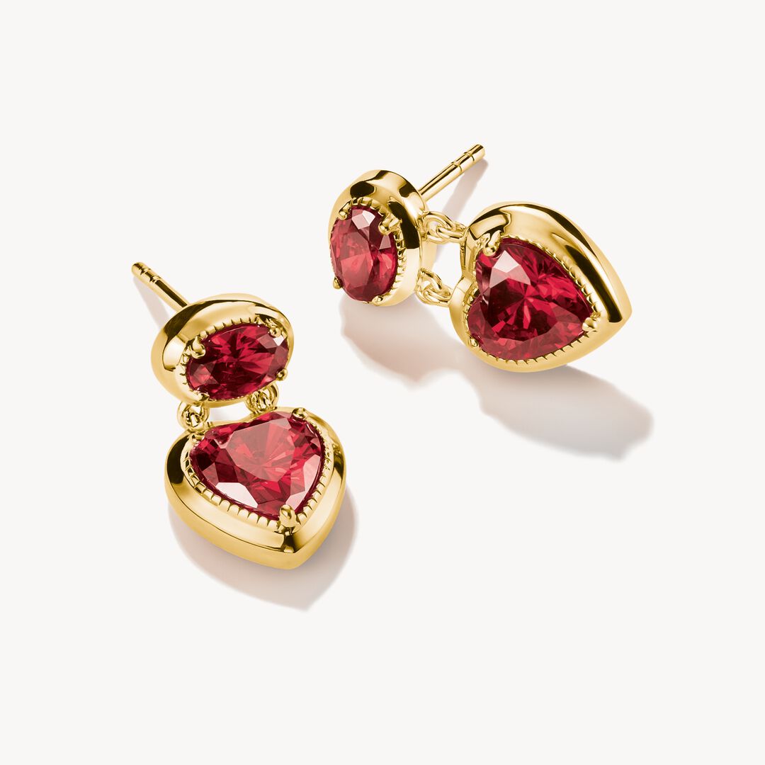 Gold earrings with red heart-shaped gemstones on a white background