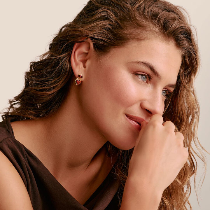 Woman wearing a heart-shaped earring with a beige background