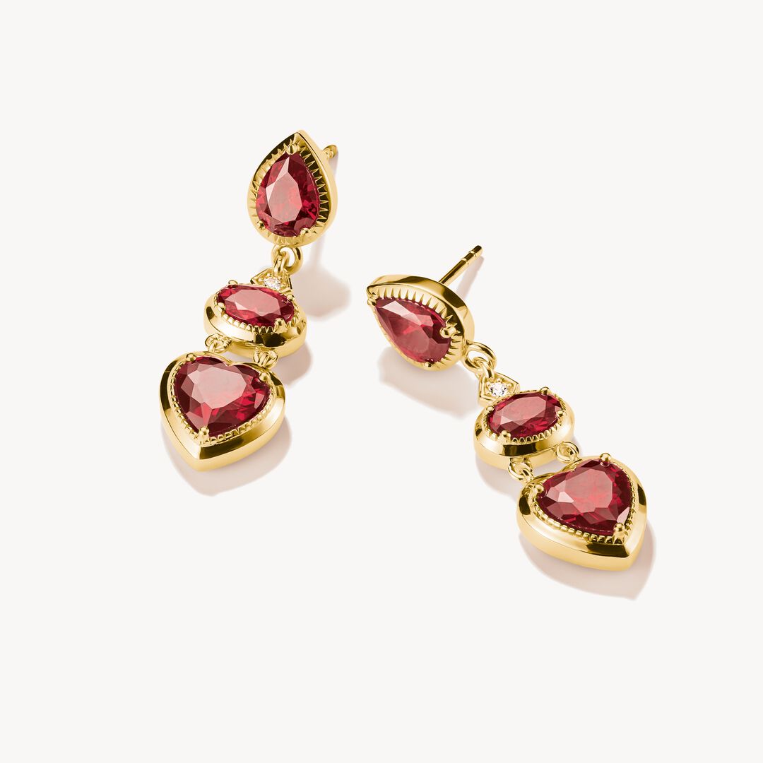 Gold earrings with red gemstones on a white background