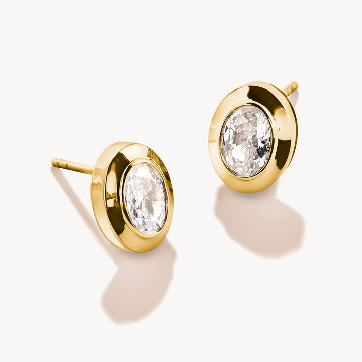 Gold earrings with clear gemstones on a white background
