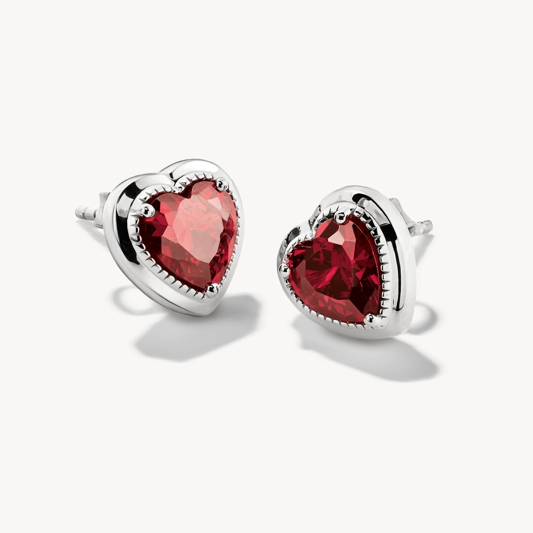 Heart-shaped earrings with red gemstones on a white background