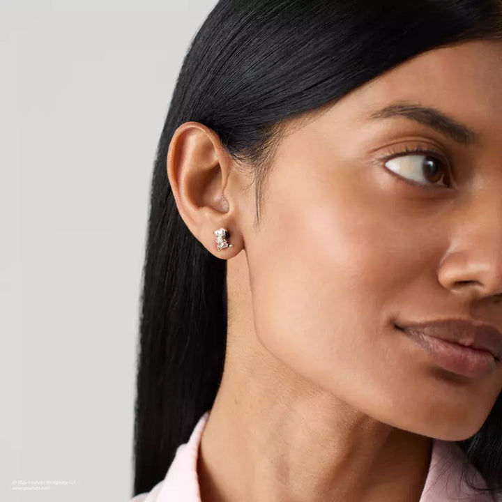 Close-up of a woman wearing a diamond earring on a neutral background