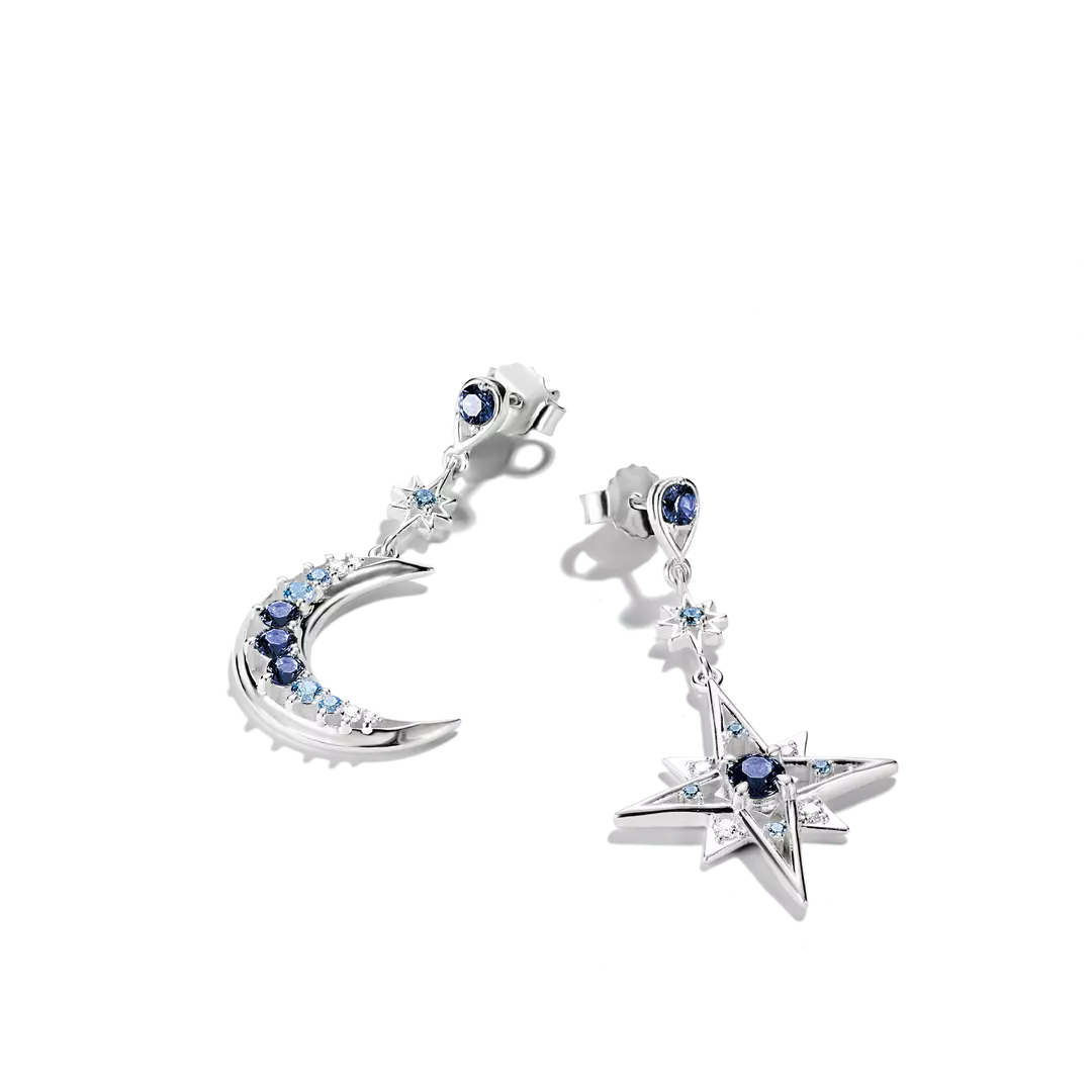 A pair of silver-toned dangle earrings featuring a large star and a crescent moon, both adorned with dark blue round gemstones and small light blue cubic zirconia accents, shown on a white background.