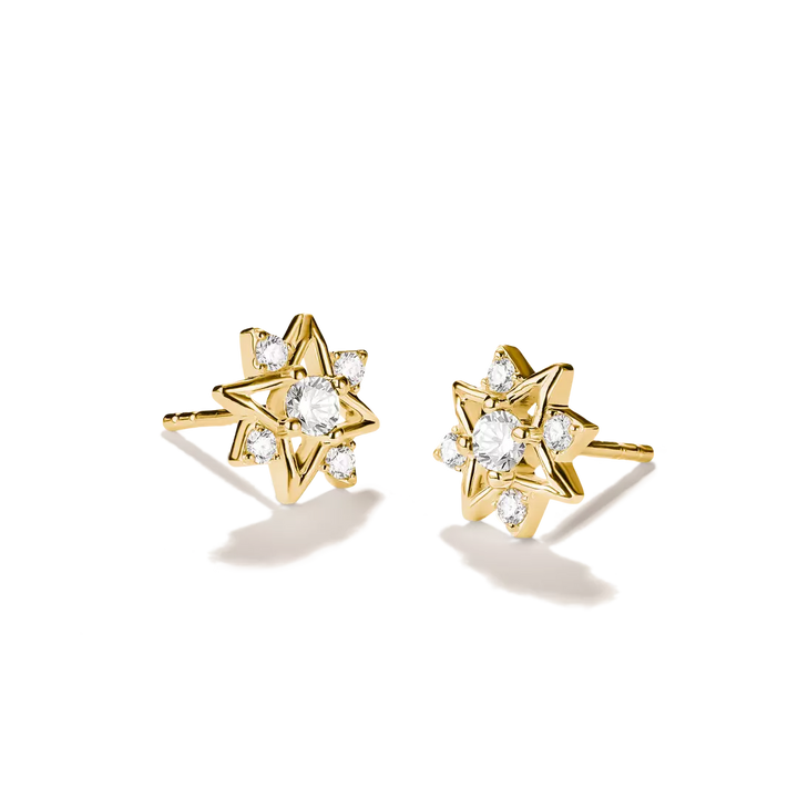A pair of gold starburst stud earrings with clear gemstones, displayed on a clean white background with soft shadows.