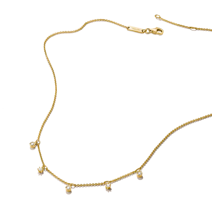 A delicate gold chain necklace with five small, clear crystal bead charms spaced along the front, displayed on a clean white background.