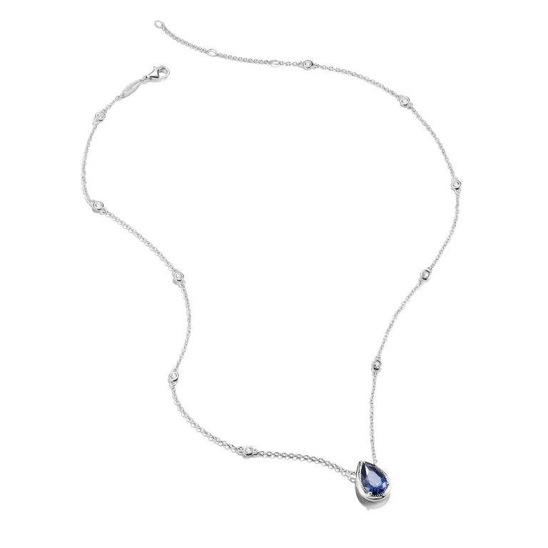 A delicate silver-toned necklace featuring a teardrop-shaped blue gemstone pendant, displayed on a clean white background.